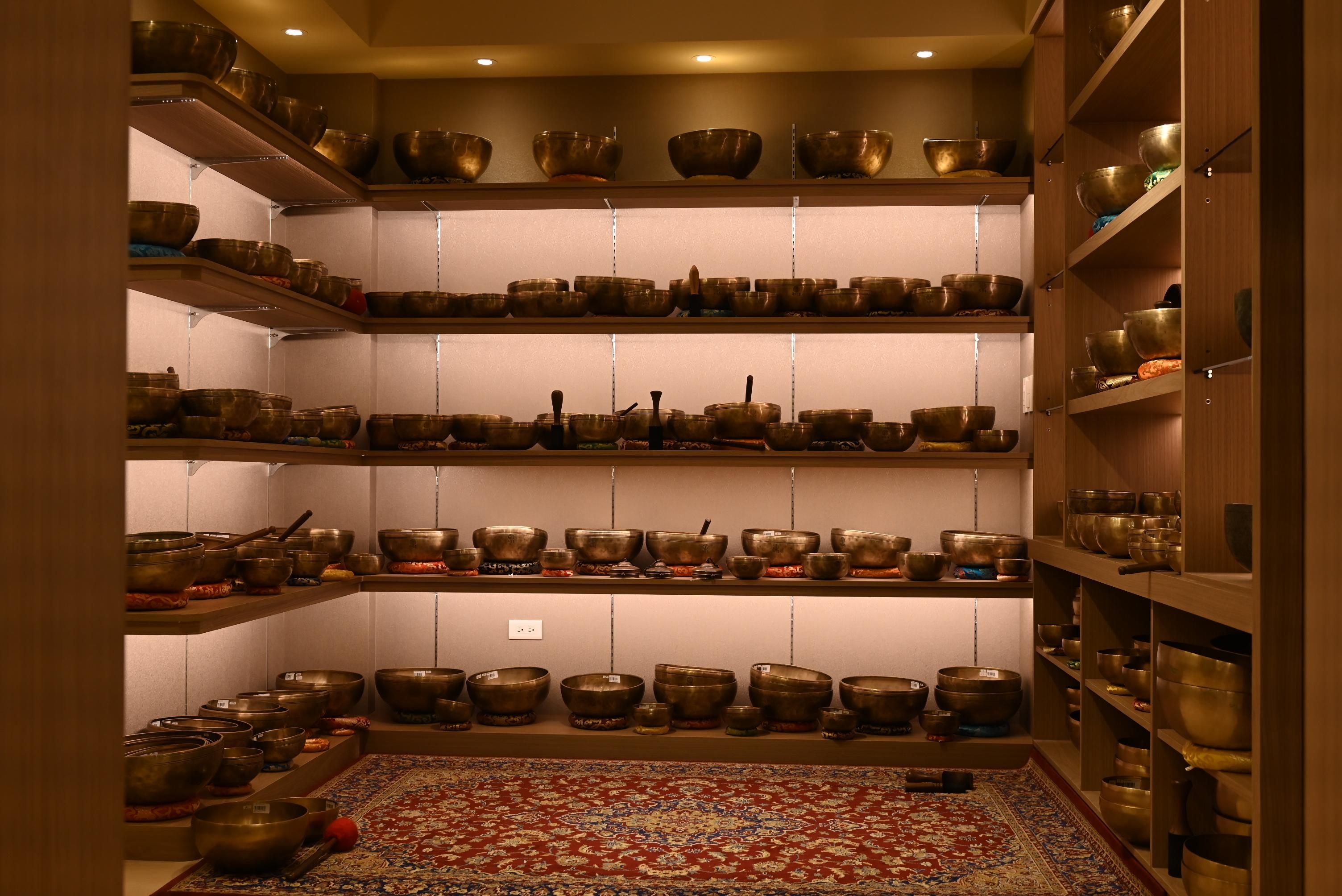 Shelves of therapeutic singing bowls in the studio's 600-bowl library